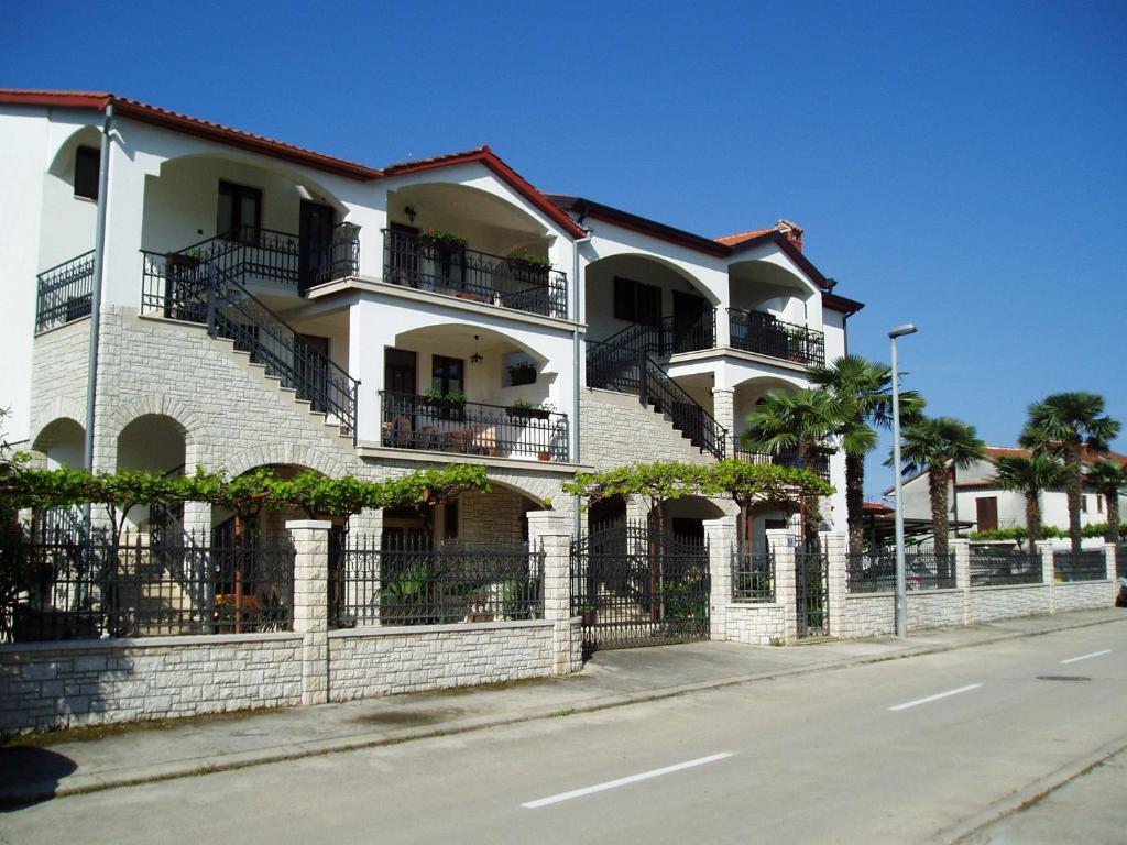 biały ceglany budynek z balkonami na ulicy w obiekcie Apartments Modrušan w Rovinj