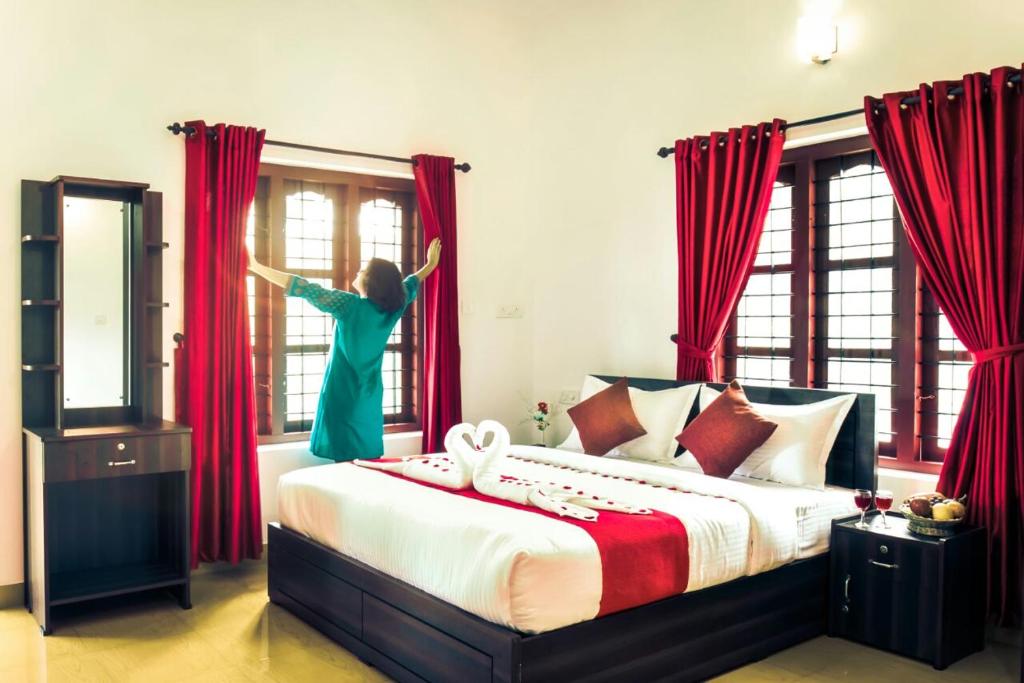 Una donna che salta dal letto in una camera da letto di Three Roots Resort a Sultan Bathery