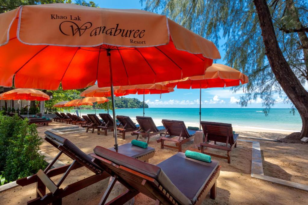 a group of chairs and umbrellas on a beach at Khaolak Wanaburee Resort - SHA Extra Plus in Khao Lak