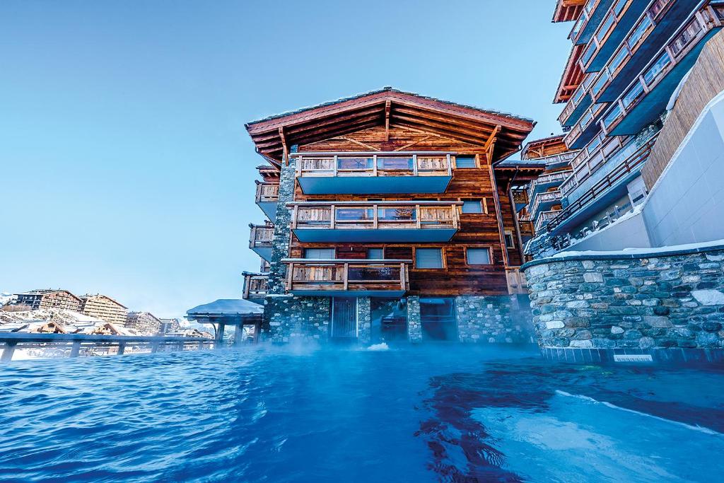 a hotel on the water next to a building at Nendaz 4 Vallées & SPA 4* Superior in Nendaz