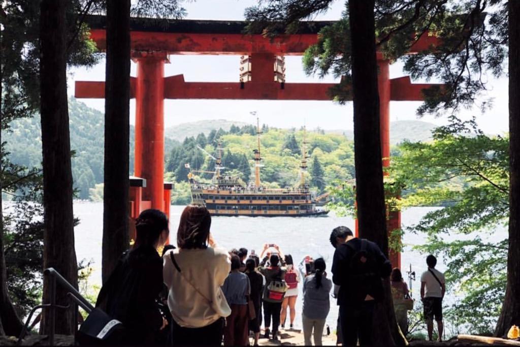 un groupe de personnes se tenant devant une porte torii dans l'établissement Ashinoko Port Villa MIRAHAKONE, à Hakone
