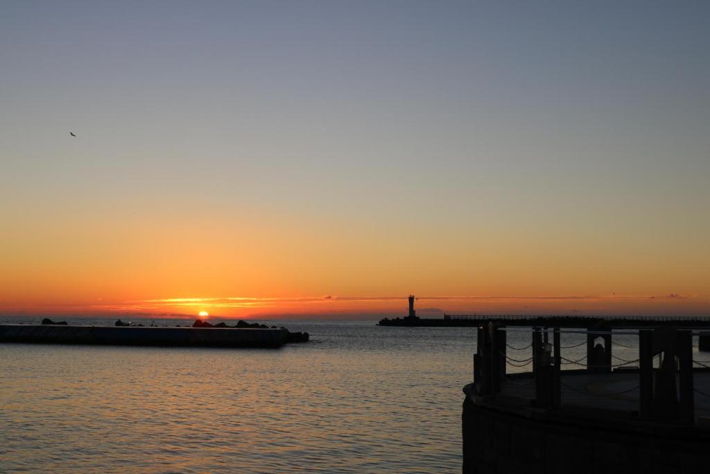 a sunset over a body of water with a pier at Guest House MARUYA in Atami