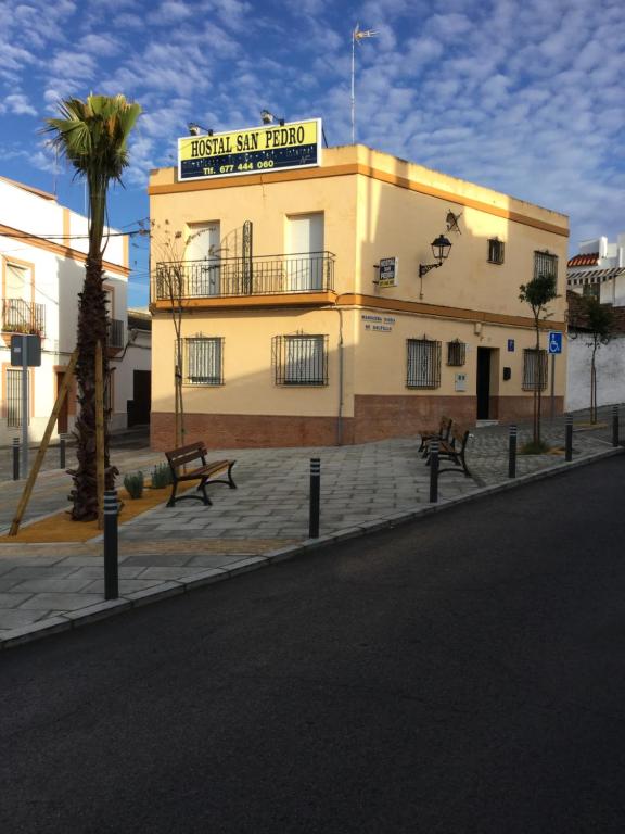 a white building with a blue sky and palm trees at Hostal San Pedro in Sanlúcar la Mayor