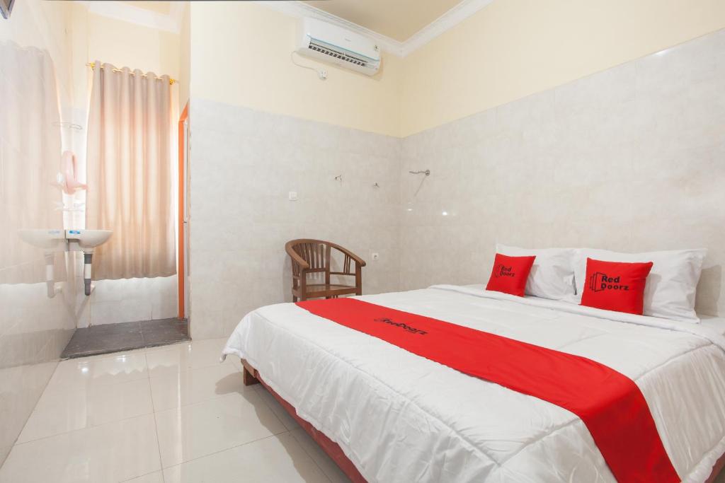 een slaapkamer met een groot bed met rode kussens bij RedDoorz Syariah At Sedati in Surabaya