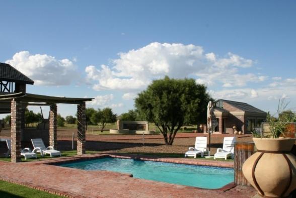 Bloemhof的住宿－Almar Exclusive Game Ranch，一个带躺椅和凉亭的游泳池