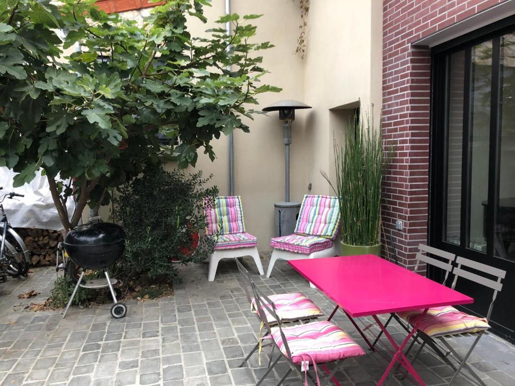 un patio avec une table et des chaises roses et un barbecue dans l'établissement La petite pause, à Montreuil