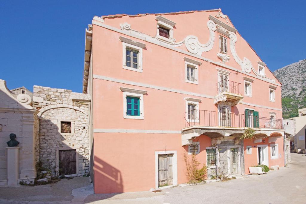 un edificio rosa con balcón en una calle en Villa Igrane, en Igrane