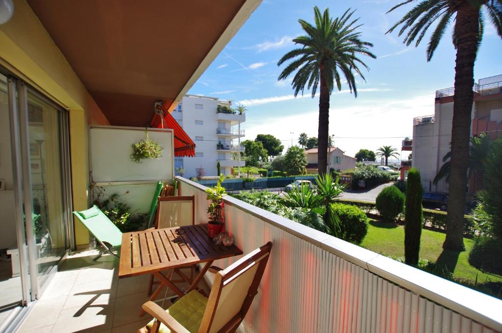 einen Balkon mit einem Tisch, Stühlen und Palmen in der Unterkunft Le lutin in Saint-Laurent-du-Var