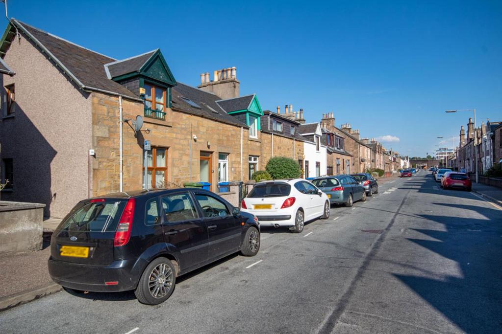 a row of cars parked on the side of a street at Innes Street Apartments in Inverness