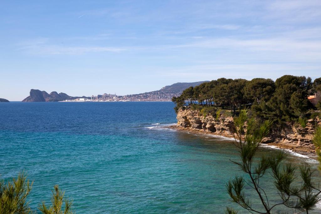 Blick auf einen Strand mit Bäumen und das Meer in der Unterkunft Hôtel Corniche du Liouquet in La Ciotat