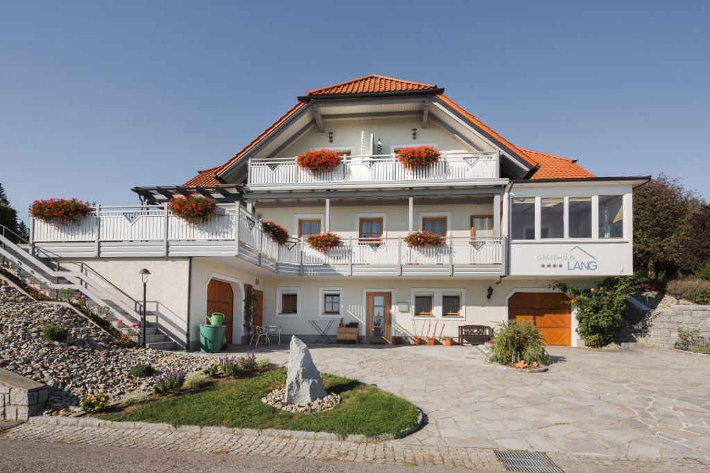 una gran casa blanca con flores en el balcón en Gästehaus Pension Lang en Pfarrkirchen im Mühlkreis