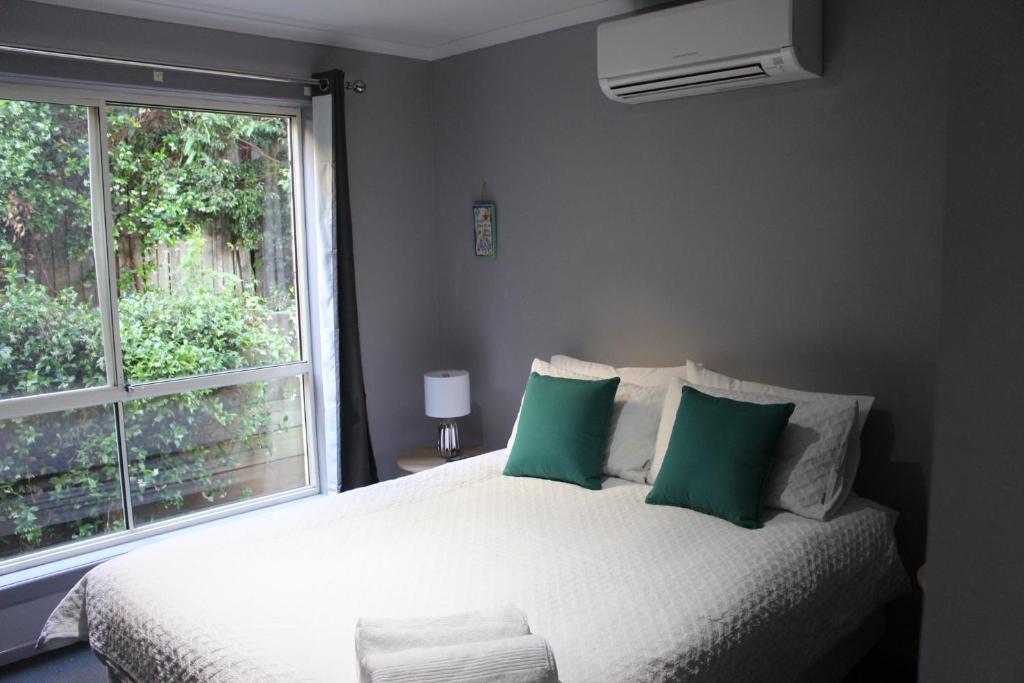 a bedroom with a bed with green pillows and a window at Aqualuna Apartments in Coffs Harbour