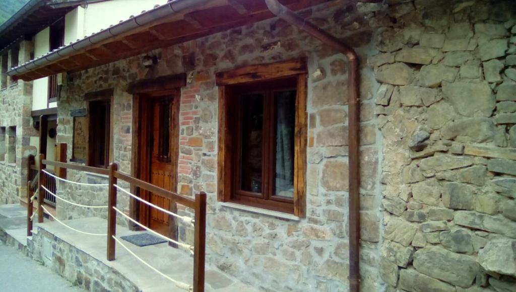 un edificio de piedra con puerta de madera y balcón en LA RAMA DEL CASTOR en Espinama