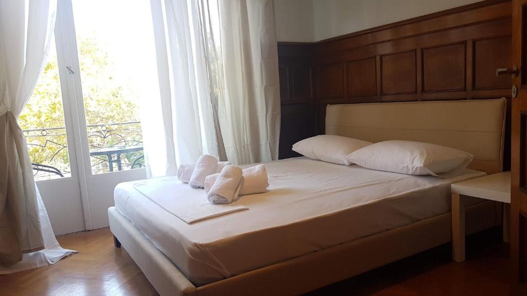 Un dormitorio con una cama con almohadas blancas y una ventana en Violet Errathens Apartment - Athens Center, 7 BD, 3 BATH en Atenas