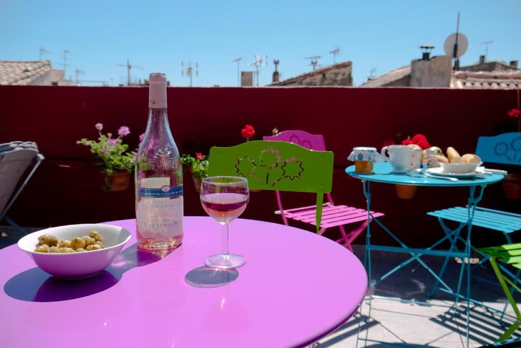 - une table rose avec une bouteille de vin et un bol de nourriture dans l'établissement La Maison de Thaïs, à Arles