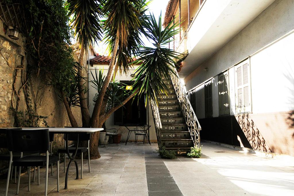 a hallway with chairs and a table and palm trees at Mosaics aprtm touching Acropolis in Athens