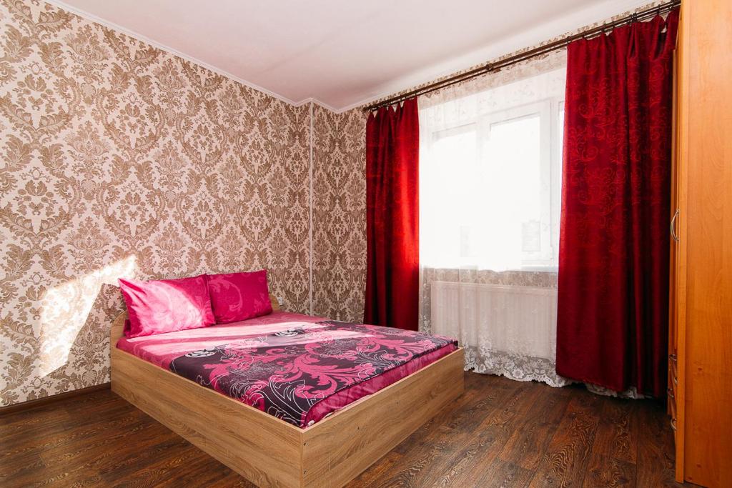 een slaapkamer met een bed en een raam met rode gordijnen bij Apartmens Faraon On Illinskaya 5 floor New Building in Sumy