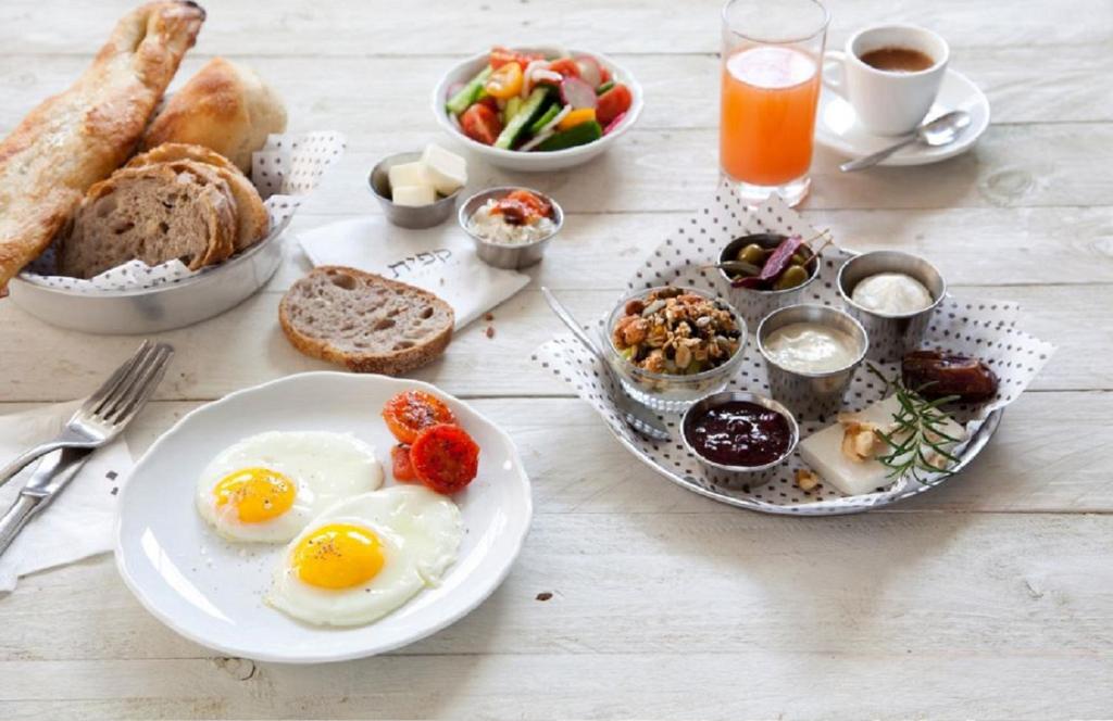 a table with eggs and bread and a plate of food at Villa Brown Moshava - a member of Brown Hotels in Jerusalem