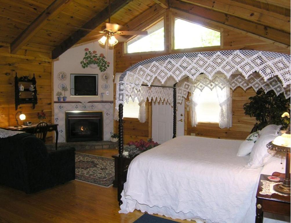 um quarto com uma cama branca e uma lareira em Black Forest Bed & Breakfast em Helen