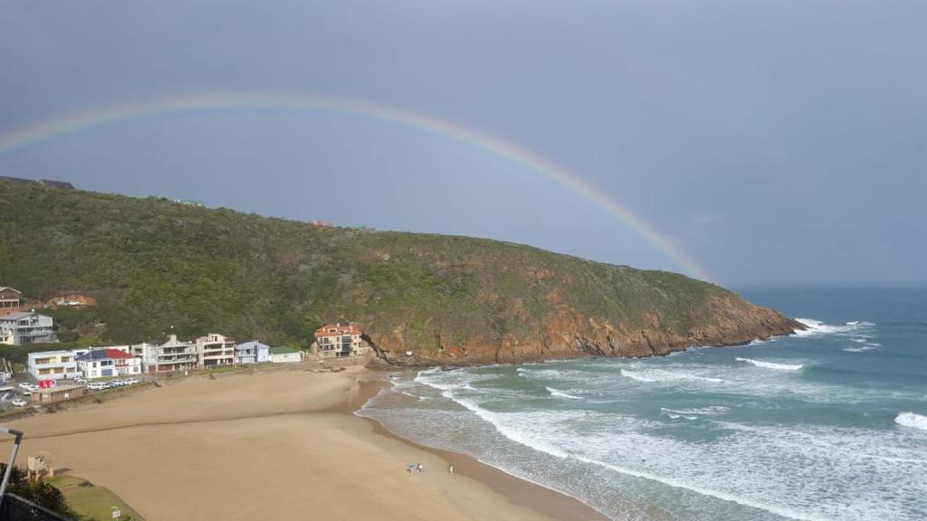 a view of a beach with a rainbow in the sky at Top beach studio in Herolds Bay