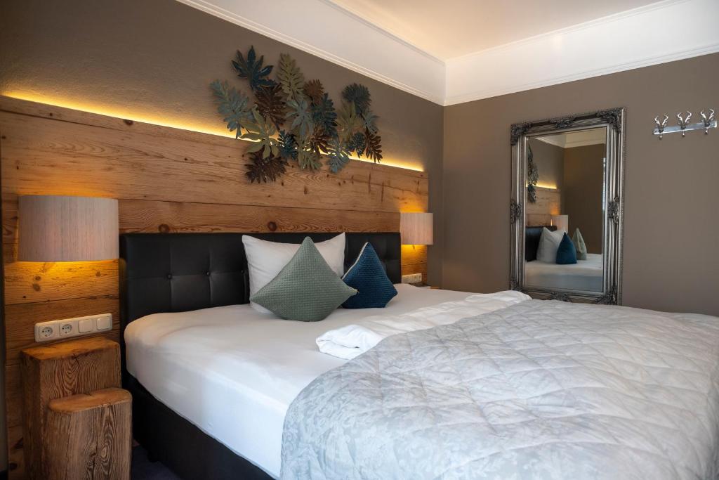 a bedroom with a large white bed and a mirror at Gartenhotel Salzach in Burghausen