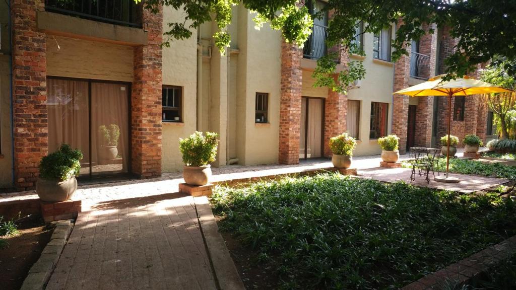 a patio with an umbrella in front of a building at 24 Onvrey Guest House in Boksburg