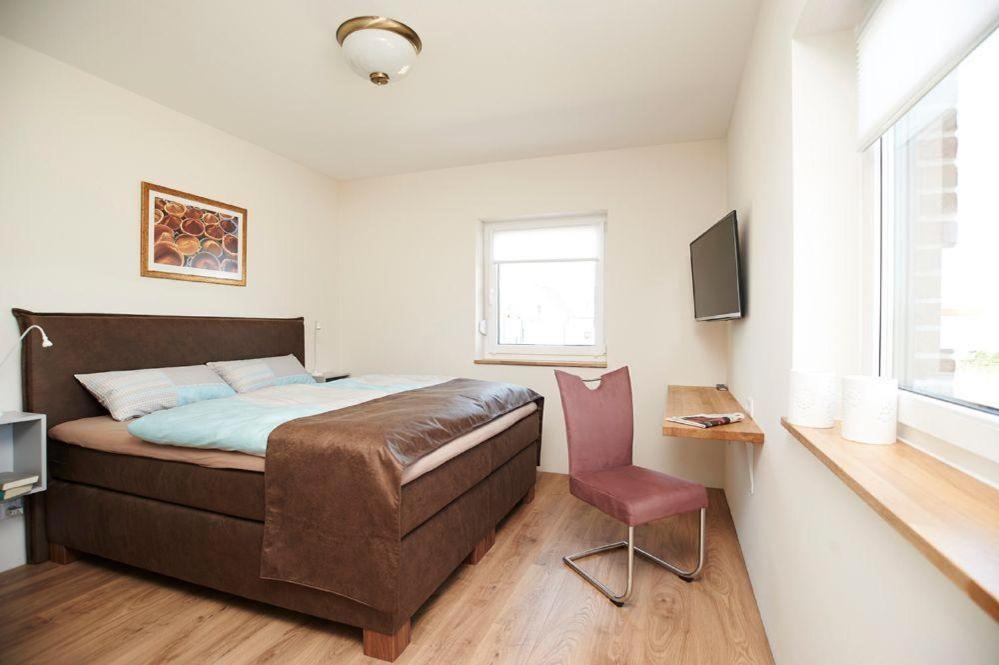 a bedroom with a bed and a chair and a television at FraulindnerFerien Doppelzimmer Lüneburg in Westergellersen