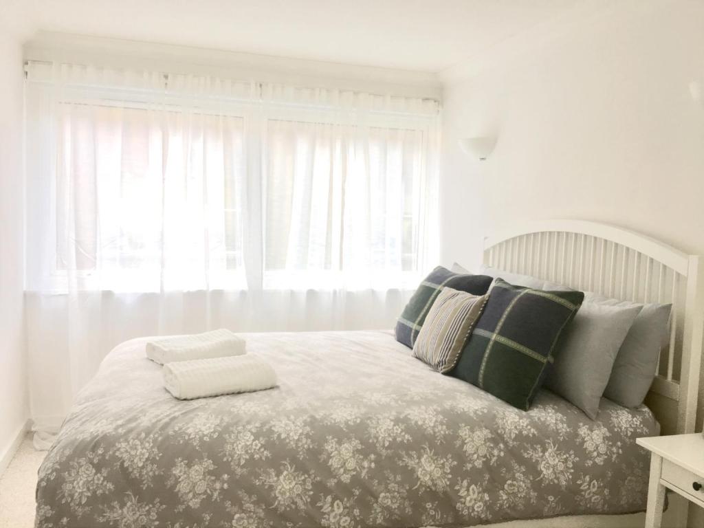een witte slaapkamer met een bed met kussens en een raam bij Splendid Fitzrovia W1 Heart of Central London 1-Bed. Free Wifi in Londen