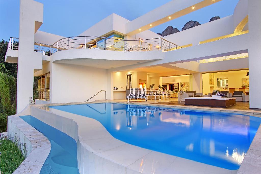 een groot huis met een zwembad ervoor bij Hollywood Mansion & Spa Camps Bay in Kaapstad