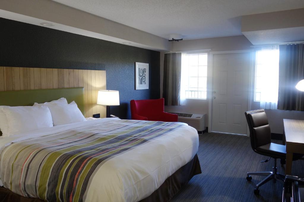 a hotel room with a bed and a red chair at Country Inn & Suites by Radisson, Pigeon Forge South, TN in Pigeon Forge