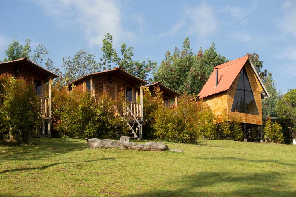 un par de cabañas en un patio con un tronco en Cabanas Villa Helena, en Guatavita