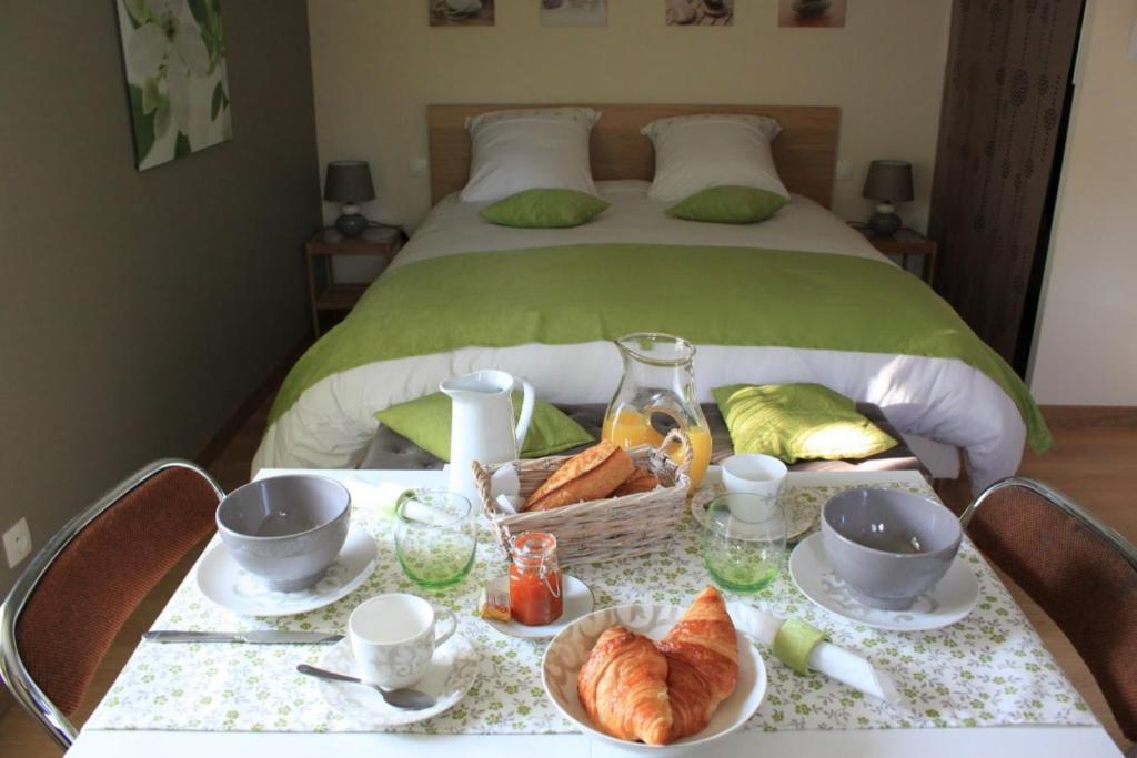 a table with a basket of croissants and a bed at Chambre d'hotes Antony in Fresnes