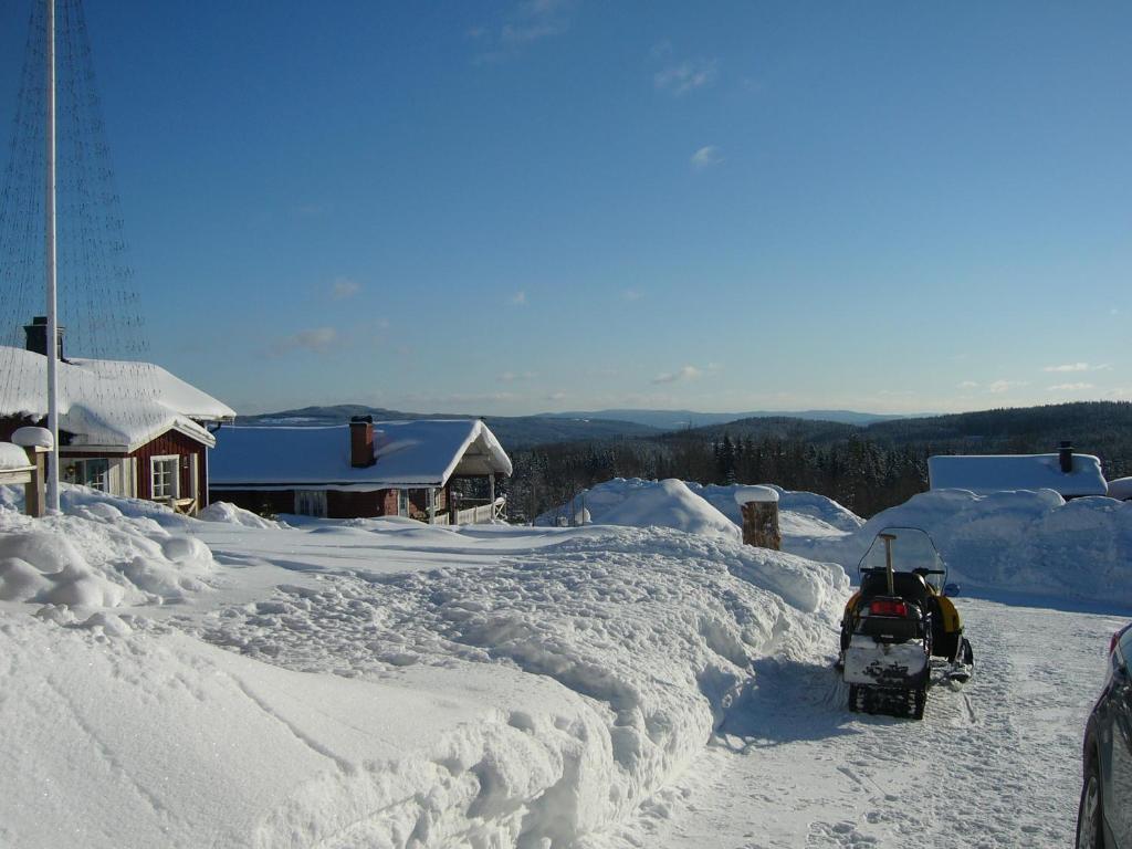 une cour recouverte de neige avec un bulldozer dessus dans l'établissement Panoramaboende, à Torsby