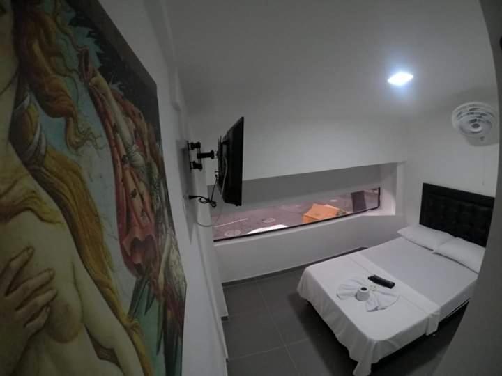 um pequeno quarto com uma cama e uma televisão em Hotel zona express sandiego em Medellín