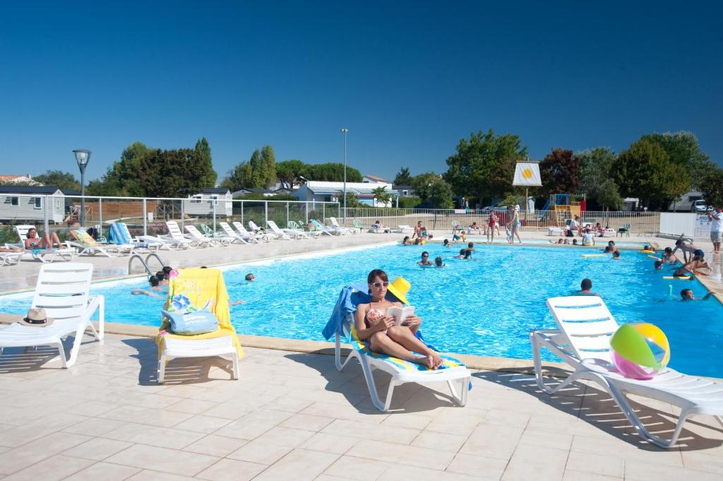 a man sitting on a chair next to a swimming pool at Azureva Fouras in Fouras