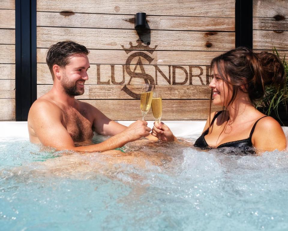 un hombre y una mujer en un jacuzzi con copas de vino en Lusandre, en Olen