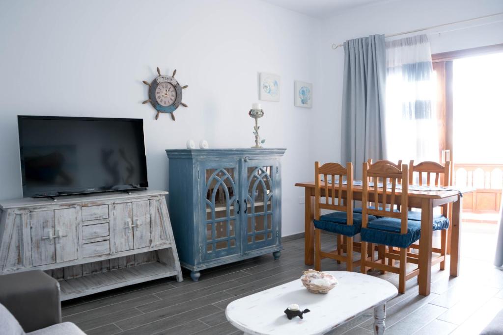 a living room with a tv and a table and chairs at Close to Everything | A/C+ WiFi | 1min Beach | in Los Cristianos
