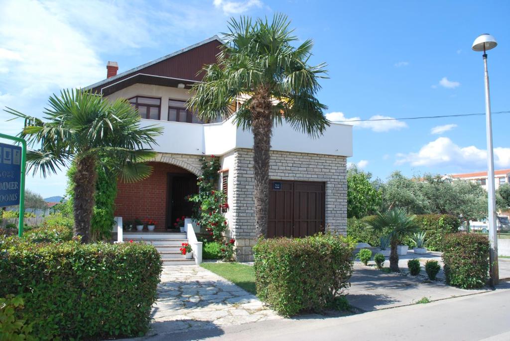 a house with two palm trees in front of it at Guesthouse Ema in Sukošan