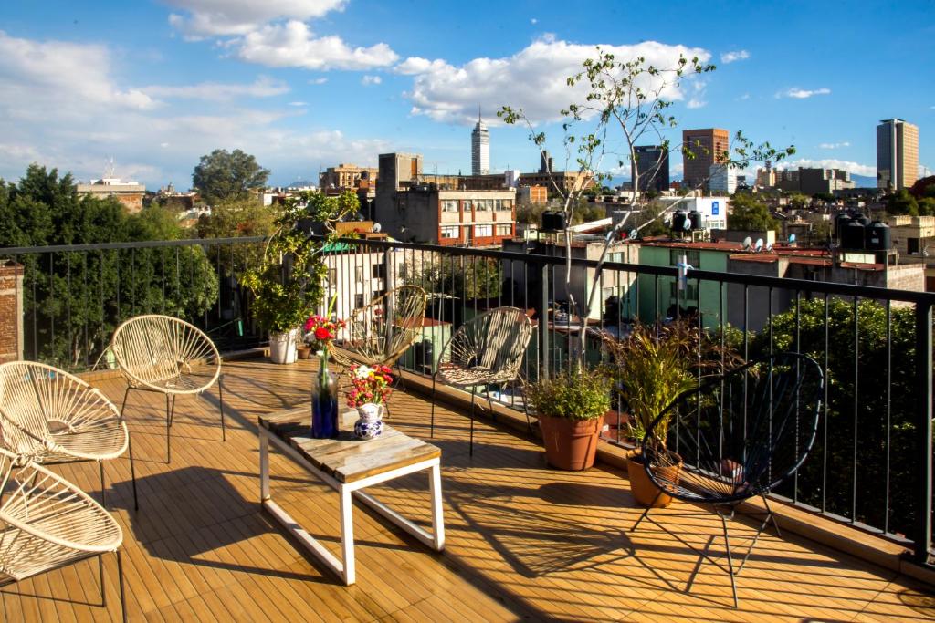 a balcony with chairs and tables and a view of a city at Casa Índigo CDMX in Mexico City