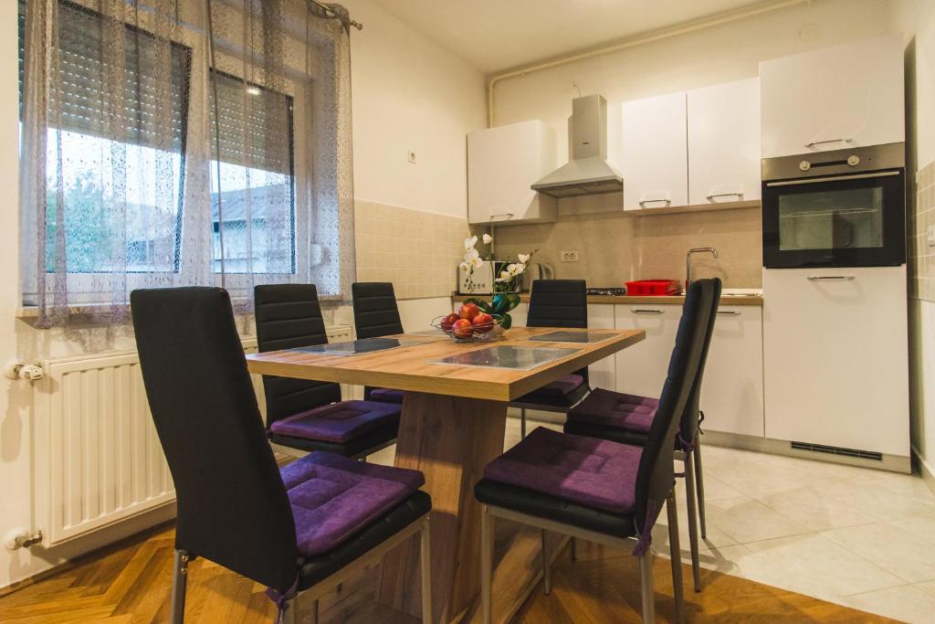 une cuisine avec une table en bois et des chaises violettes dans l'établissement Apartments "Pavić" near Zagreb Airport, à Velika Gorica