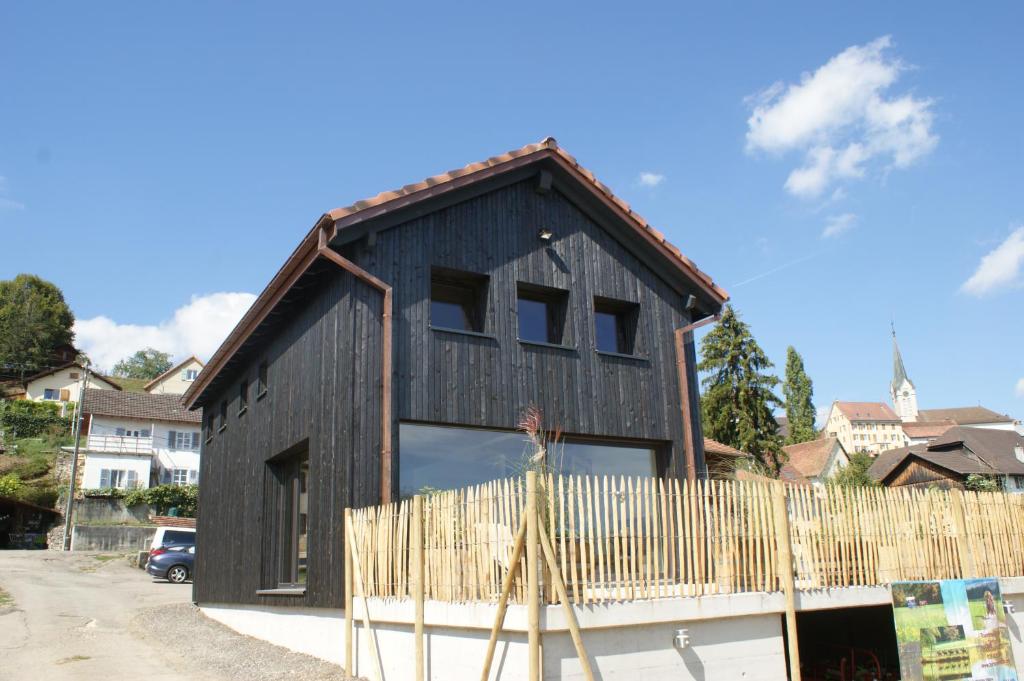 ein schwarzes Haus mit einem Holzzaun davor in der Unterkunft L'hôtât di loup in Courtedoux