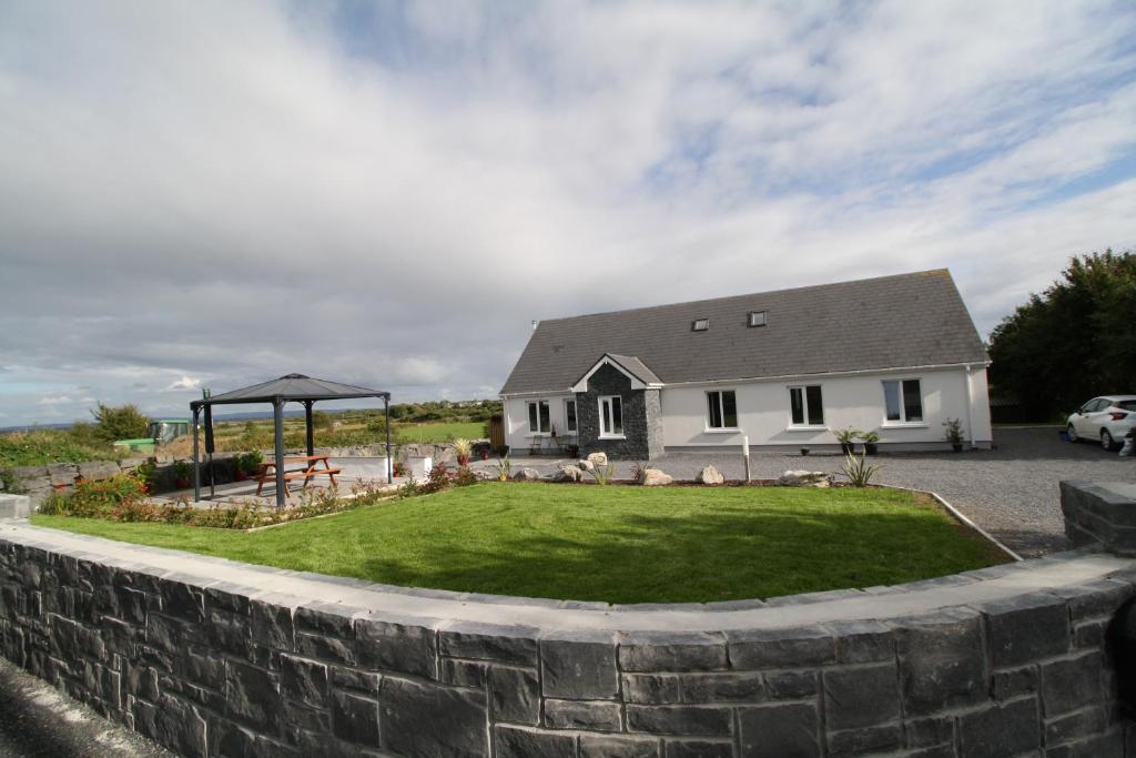 una casa con una pared de retención y un patio en Atlantic Retreat Lodge, en Kinvara