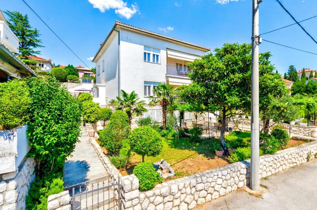 a house with a stone retaining wall and trees at One-Bedroom Apartment in Crikvenica V in Sopaljska
