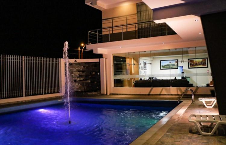 a swimming pool with a fountain in front of a building at hotel el parral suite in Ica