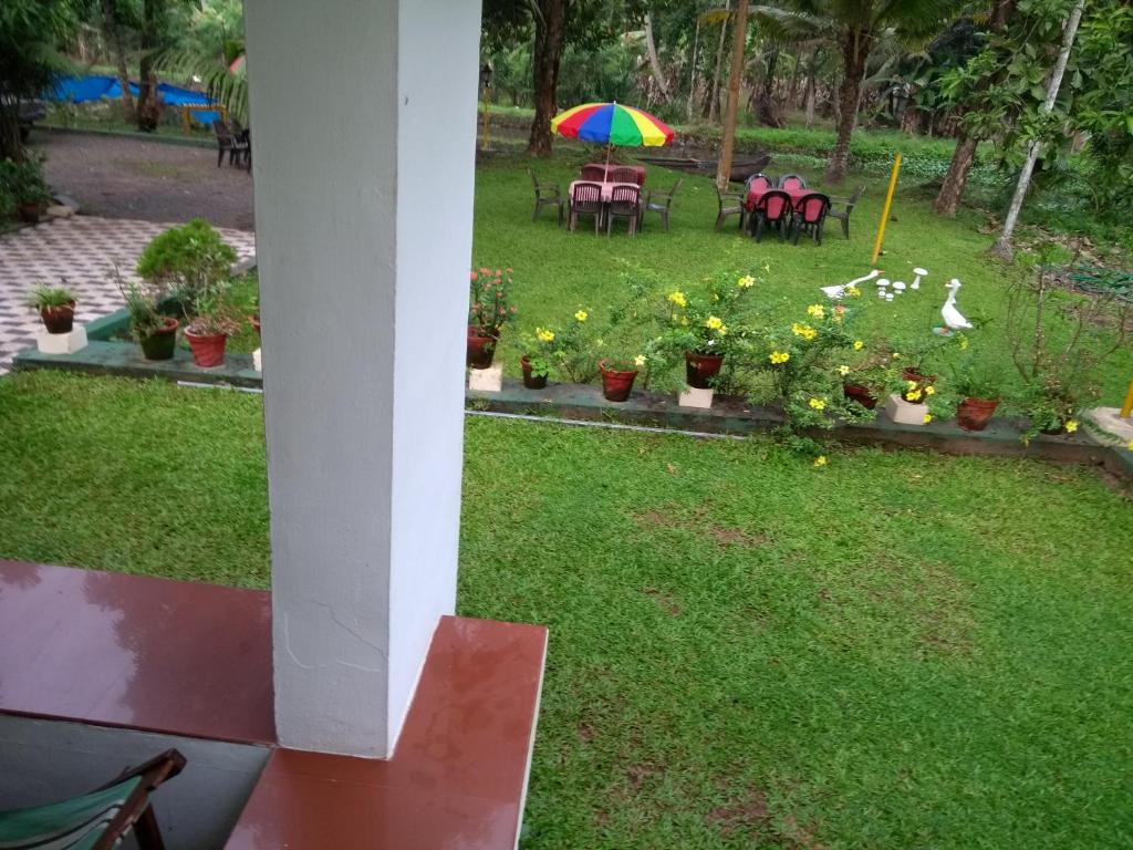 a garden with a table and chairs and an umbrella at Aqualillies Water Front Heritage Homestay in Kumarakom