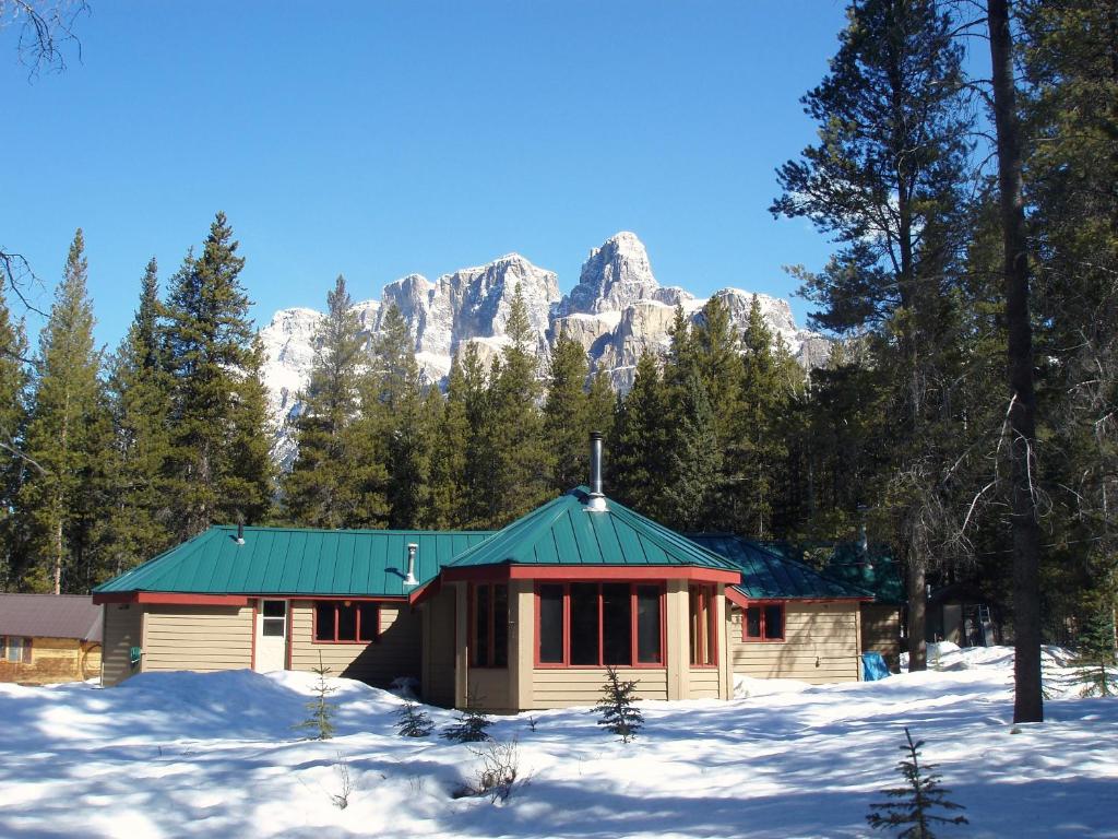 a cabin in the snow with a mountain in the background at HI Castle Mountain - Hostel in Castle Junction