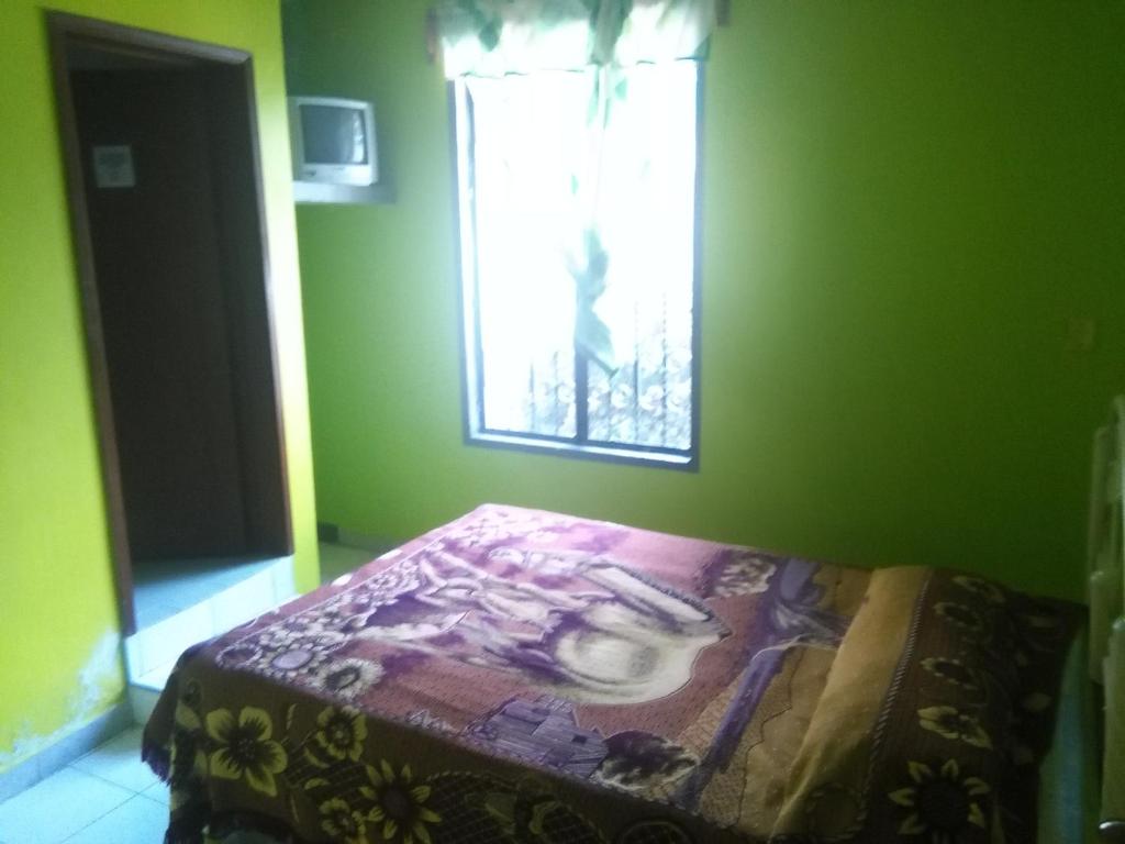 Cama en habitación verde con ventana en HOTEL MONTALVO, en Tezontepec de Aldama