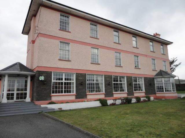 un grande edificio in mattoni con finestre bianche su un prato di Alpine Guesthouse a Dingle
