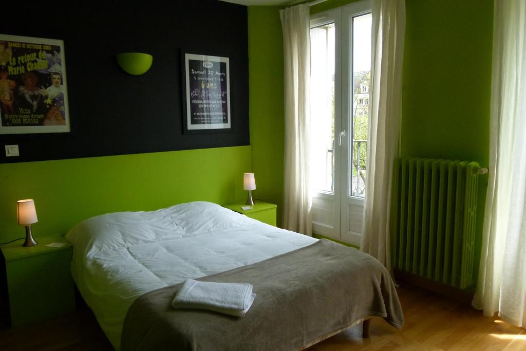 um quarto verde com uma cama e uma janela em Hôtel Victor em Beauvais