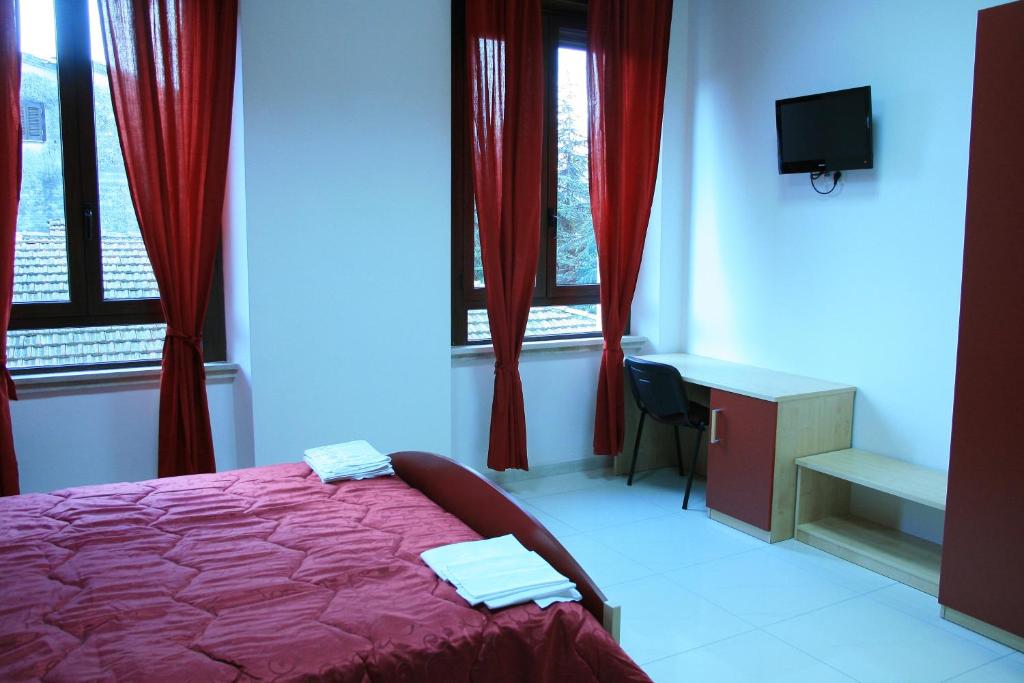 Schlafzimmer mit einem Bett mit roten Vorhängen und einem TV in der Unterkunft Albergo Ma.Re in Popoli